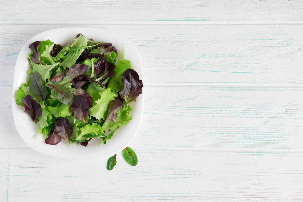 Assiette avec laitue sur fond blanc en bois. Des salades vertes. De la nourriture biologique. Nourriture pour végétaliens. Concevoir une bannière avec de la nourriture naturelle
. - Photo, image