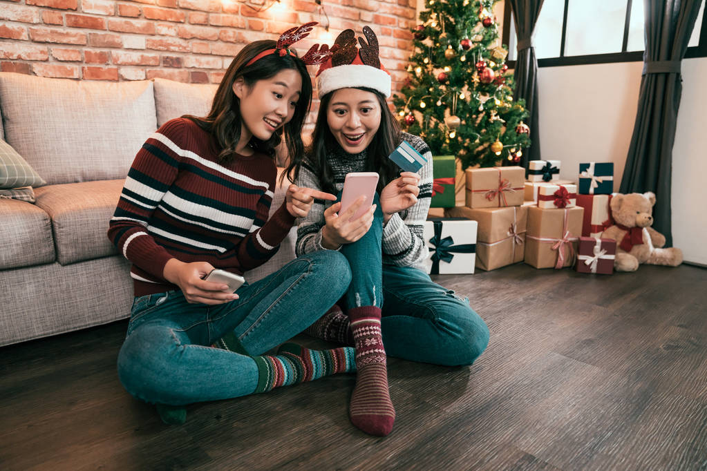 Freundinnen Handy-Shopping online zu Hause aufgeregt überrascht Zeigefinger auf Bildschirm im Internet-Shop auf Weihnachtsverkauf. junge Mädchen kaufen am Boxtag E-Commerce mit Kreditkarte - Foto, Bild