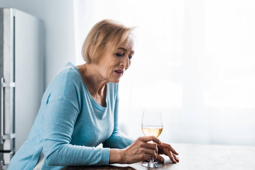 femme âgée solitaire en vêtements décontractés tenant verre de vin à la maison avec espace de copie
 - Photo, image