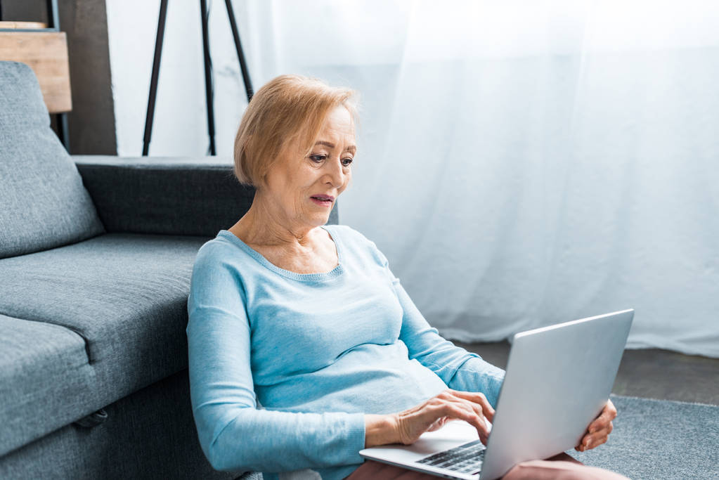 mujer mayor sentada y escribiendo en el ordenador portátil en casa
 - Foto, imagen