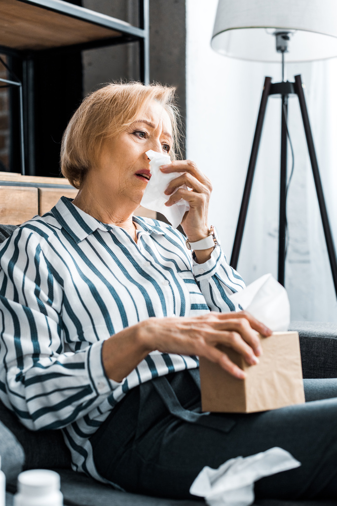 femme âgée malade avec le nez qui coule souffrant de froid et tenant boîte de tissu à la maison
 - Photo, image