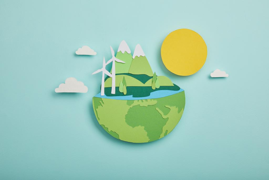 bovenaanzicht van papier knippen planeet met hernieuwbare energiebronnen op een turkooizen achtergrond, aarde dag concept - Foto, afbeelding
