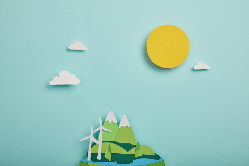 top view of paper cut planet with renewable energy sources on turquoise background, earth day concept - Photo, Image