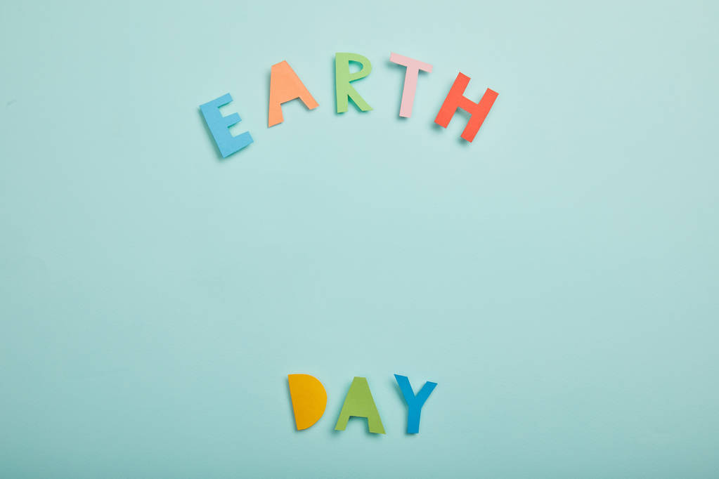 top view of colorful paper letters on turquoise background, earth day concept - Photo, Image