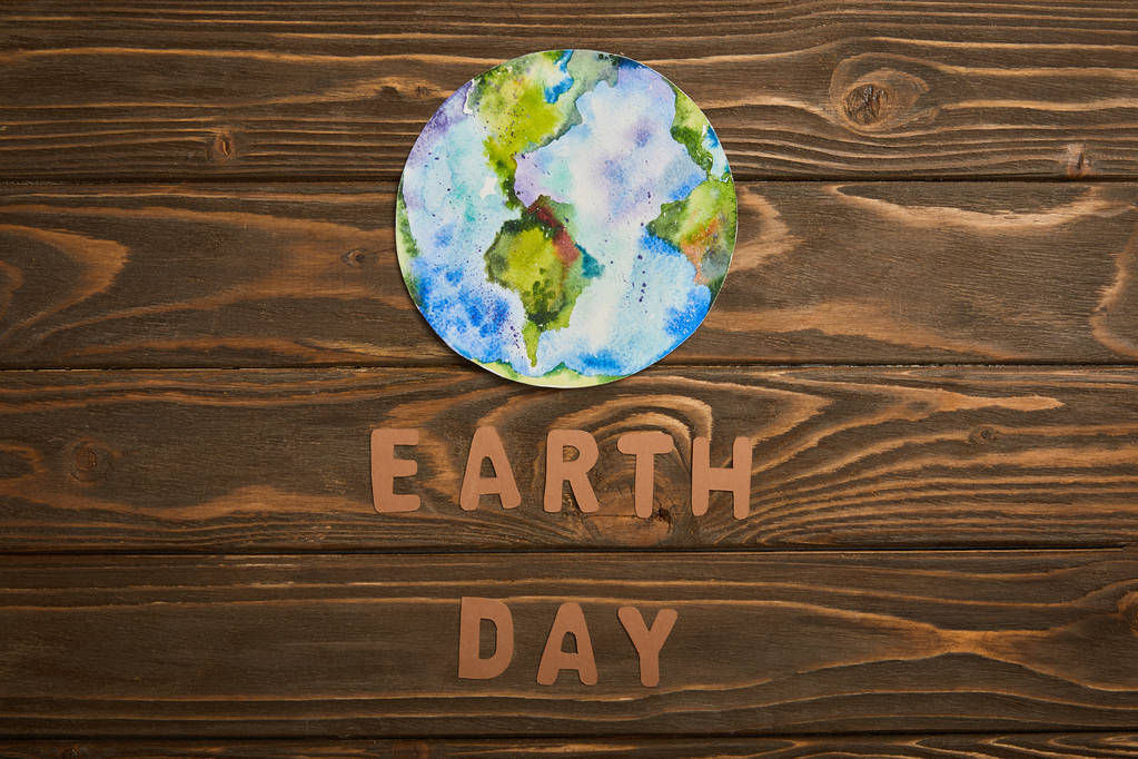 top view of paper letters and planet picture on brown wooden background, earth day concept - Photo, Image