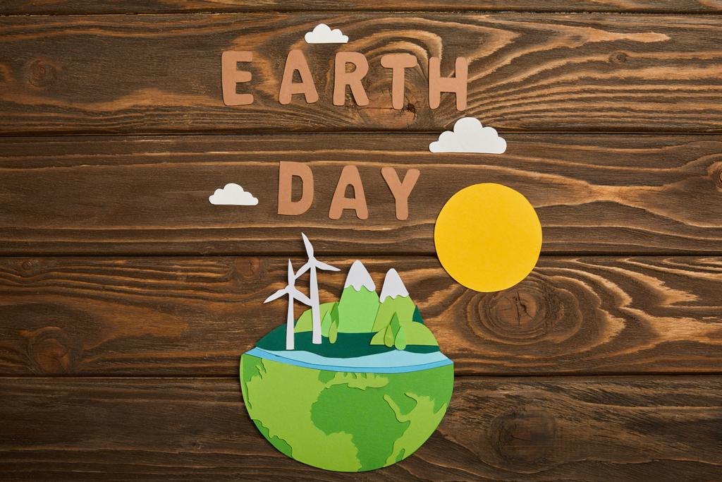 vista superior del planeta cortado en papel con fuentes de energía renovables y letras sobre fondo de madera, concepto del día de la tierra
 - Foto, Imagen
