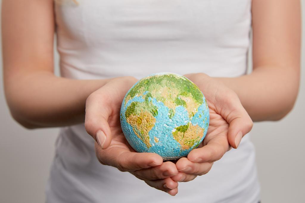 woman holding planet model on grey background, earth day concept - Photo, Image