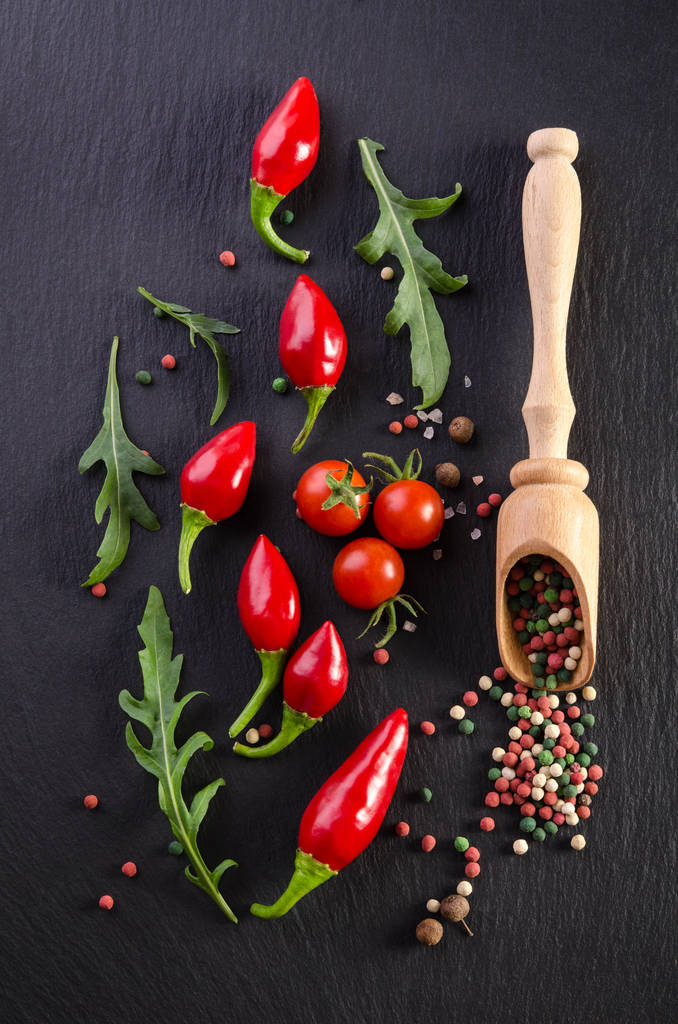 Verschillende kruiden met tomaat en paprika's op een zwarte achtergrond - Foto, afbeelding