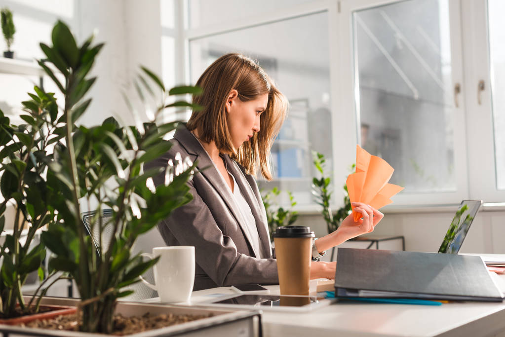 вибірковий фокус бізнес-леді, що тримає паперову площину біля ноутбука та одноразову чашку в офісі, концепція прокрастинації
 - Фото, зображення