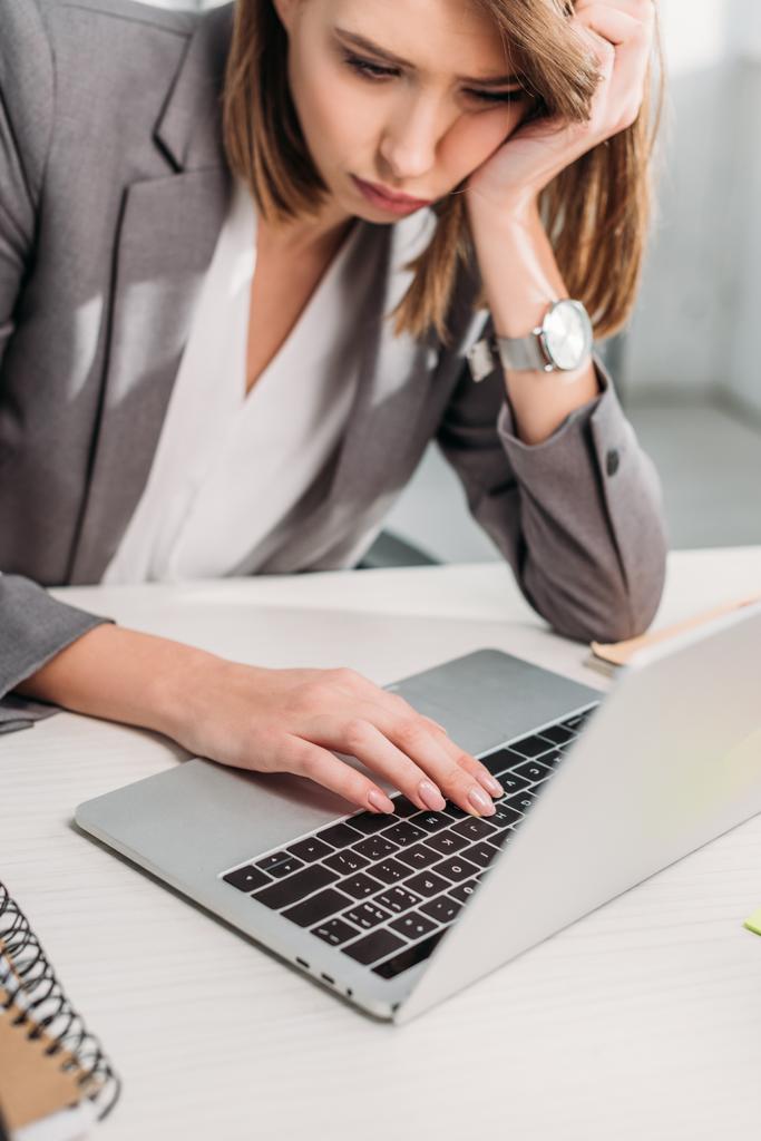 wyczerpany atrakcyjna kobieta siedzi w pobliżu laptopa w biurze  - Zdjęcie, obraz