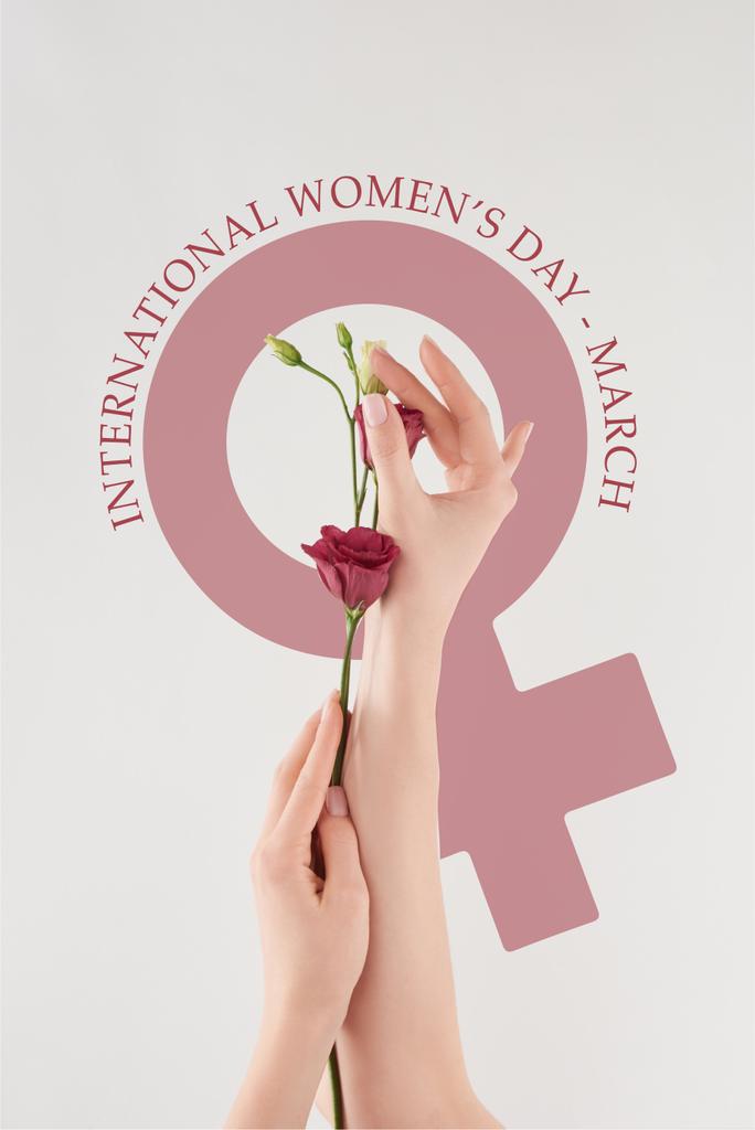 vue partielle des mains féminines avec des fleurs violettes sur fond blanc avec illustration de la journée internationale des femmes
 - Photo, image