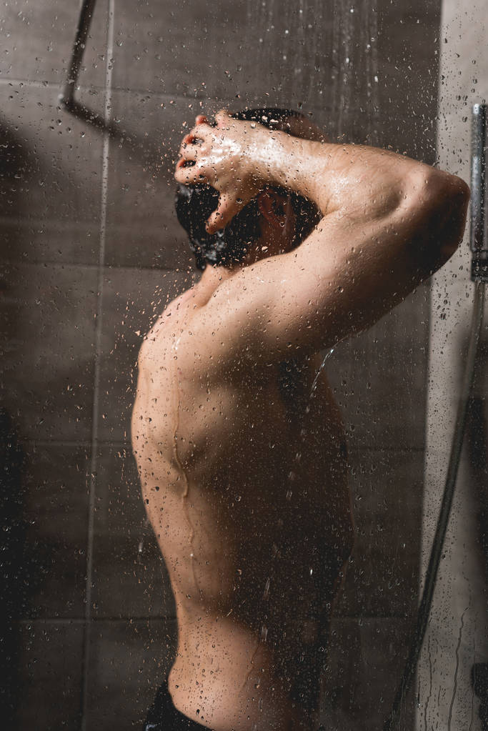 όμορφος και γυμνός άνδρας λαμβάνοντας ντους σε καμπίνα  - Φωτογραφία, εικόνα