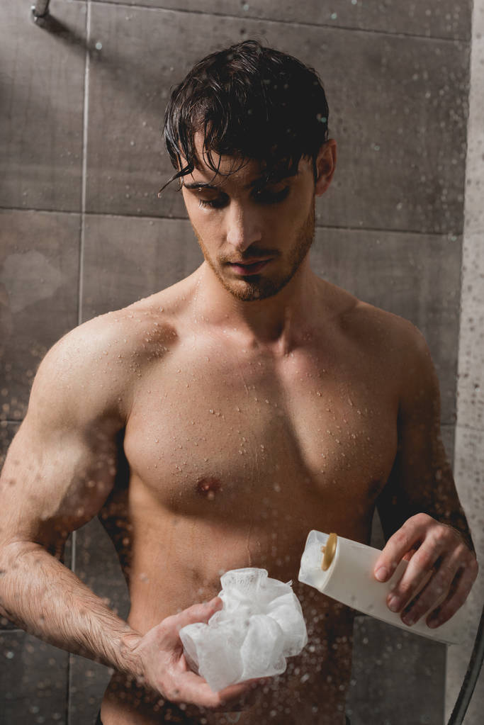 bello uomo nudo in possesso di loofah e gel doccia
  - Foto, immagini