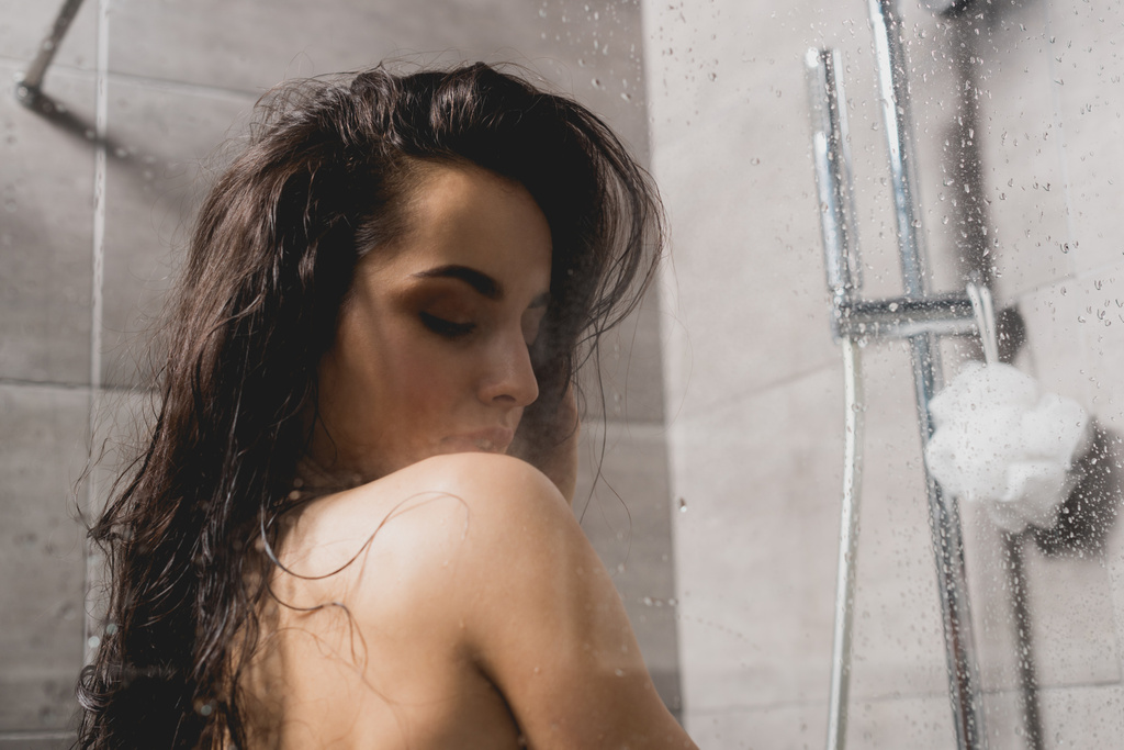 キャビンのシャワーを浴びてブルネットと裸の女性  - 写真・画像