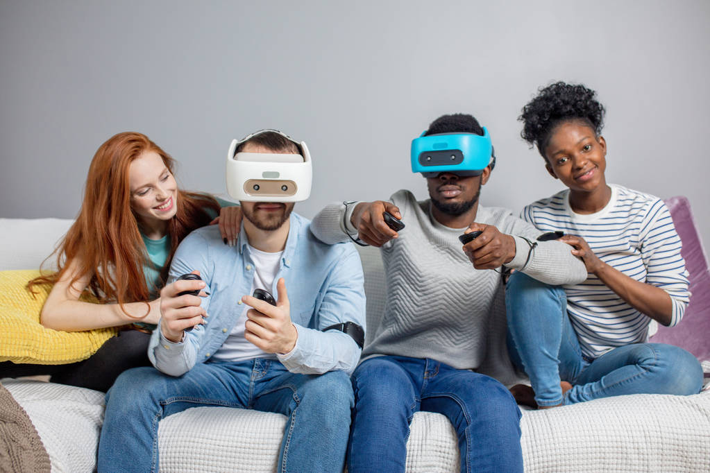 Dos chicos jugando videojuegos usando gafas VR y novias los apoyan
. - Foto, imagen