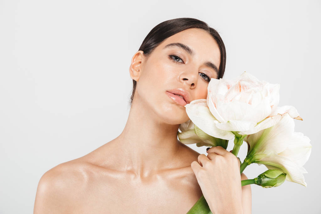 Bellezza ritratto di un attraente sensuale donna sana in piedi isolato su sfondo bianco, in posa con un fiore
 - Foto, immagini