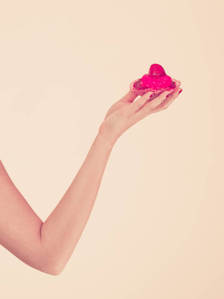 Dulces, comida gorda, concepto de azúcar. Mujer mano celebración dulce fresa cupcake
 - Foto, imagen