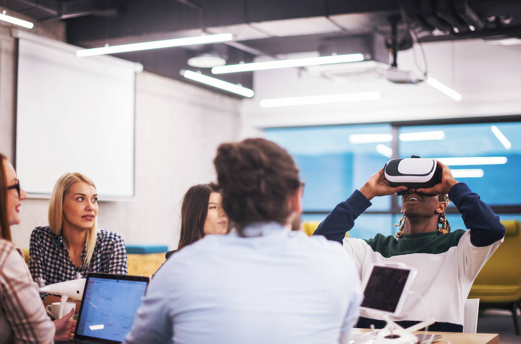 Equipo multiétnico de negocios que usa auriculares de realidad virtual en reuniones de oficina Los desarrolladores se reúnen con un simulador de realidad virtual alrededor de la mesa en una oficina creativa. - Foto, imagen
