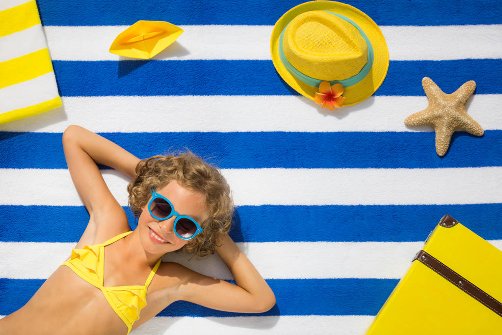 Retrato de vista superior de niño en toalla de playa rayada. Concepto vacaciones de verano
 - Foto, imagen