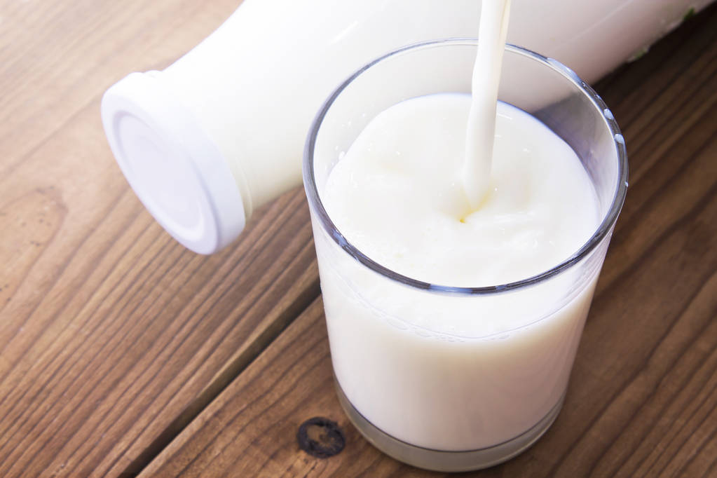 Lahvička s mlékem a sklenicí mléka na dřevěném stole - Fotografie, Obrázek