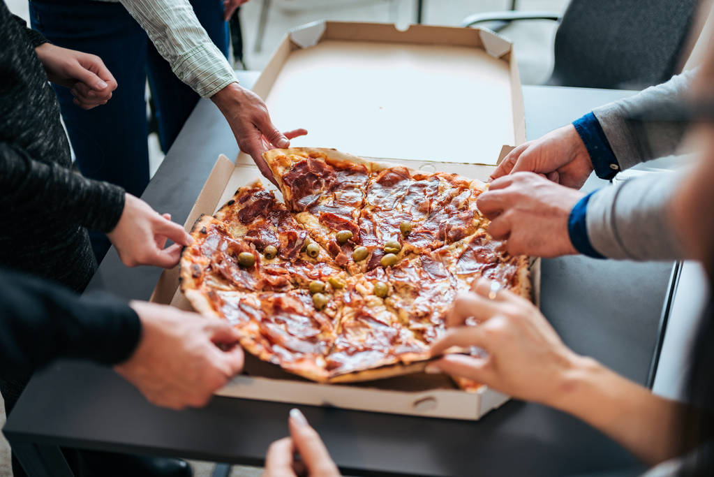 İş arkadaşlarınızla pizza yemek için ofiste paylaşımı. Üstten Görünüm. - Fotoğraf, Görsel
