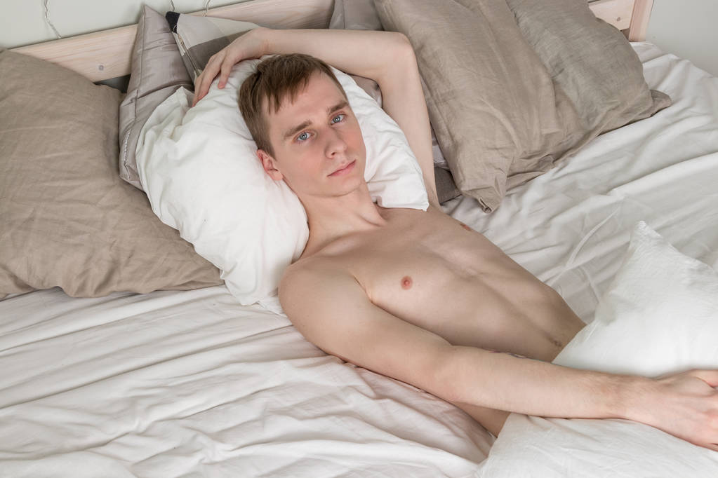 Όμορφος νεαρός ενήλικος άνδρας κοιμάται στο κρεβάτι - Φωτογραφία, εικόνα