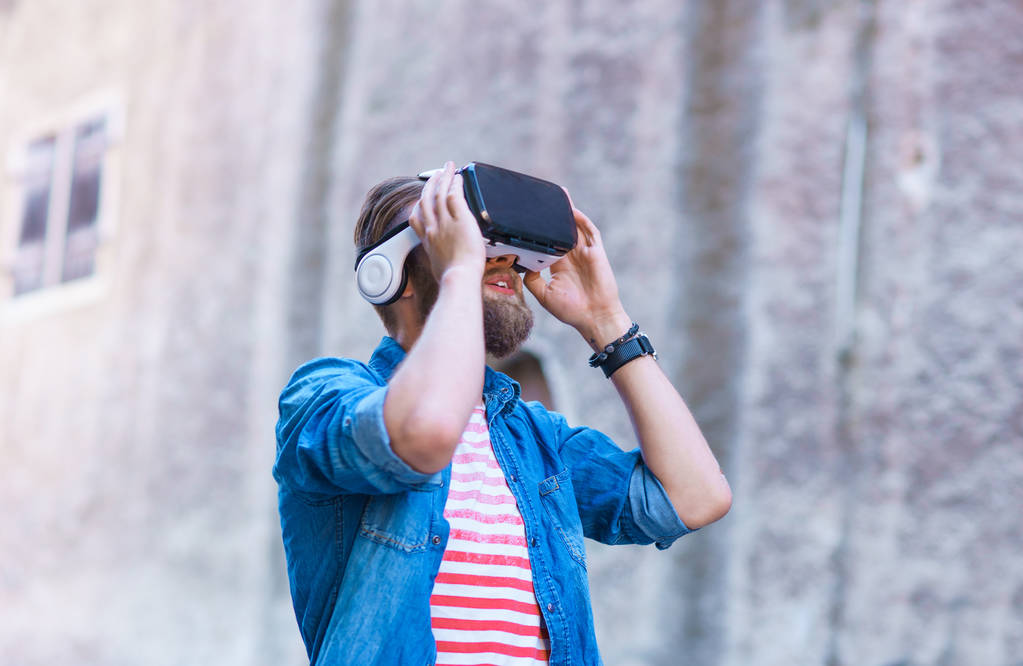 Hombre caminando por la calle con auriculares de realidad aumentada o virtual. VR, AR, dispositivos de entretenimiento y concepto de tecnología futurista
. - Foto, imagen