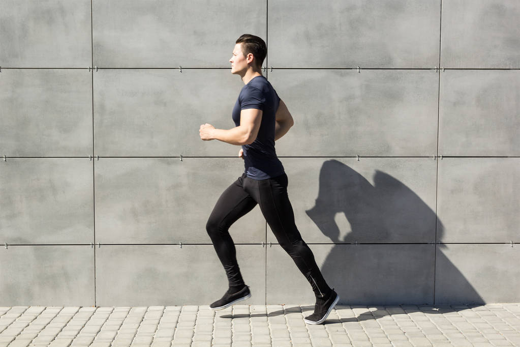 A young man runs against a gray wall, urban. - Photo, Image