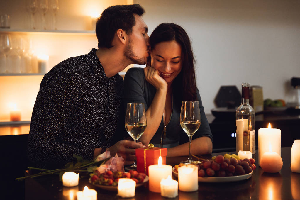 Hermosa pareja apasionada teniendo una cena romántica a la luz de las velas en casa, besándose
 - Foto, imagen