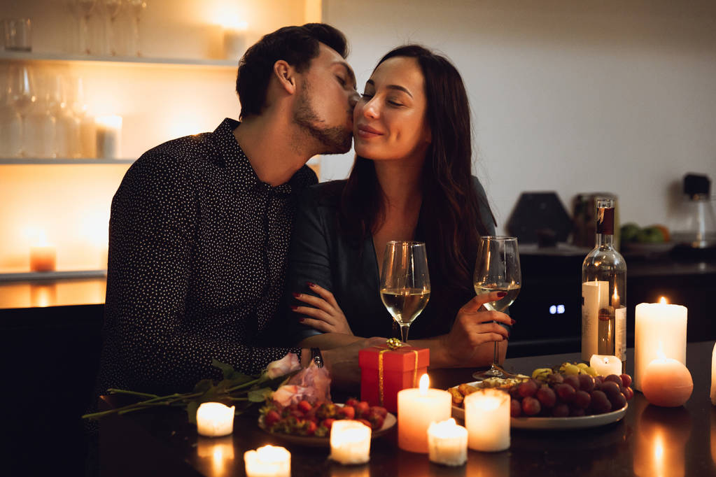 Belo casal apaixonado ter um jantar romântico à luz de velas em casa, beijando
 - Foto, Imagem