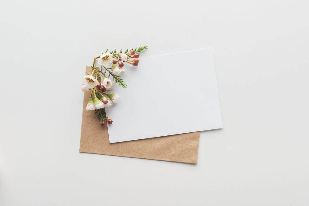 felülnézet üres üres barna kézműves papír boríték és virágok, a szürke háttér - Fotó, kép
