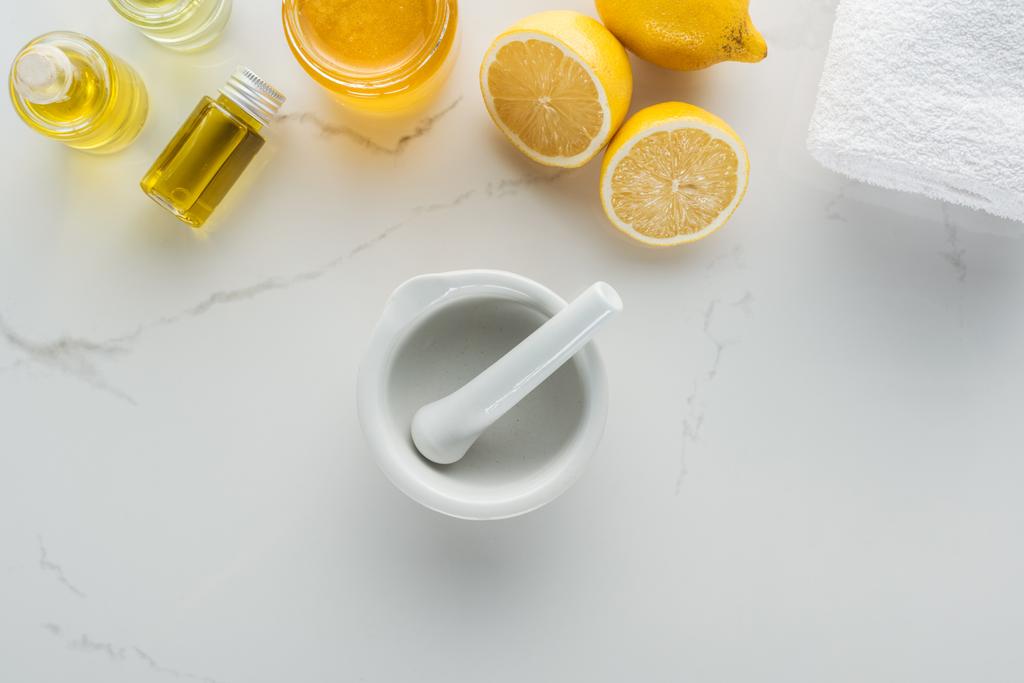 Draufsicht auf Zitronen, Pounder und verschiedene natürliche Inhaltsstoffe für die Kosmetikherstellung auf weißer Oberfläche - Foto, Bild
