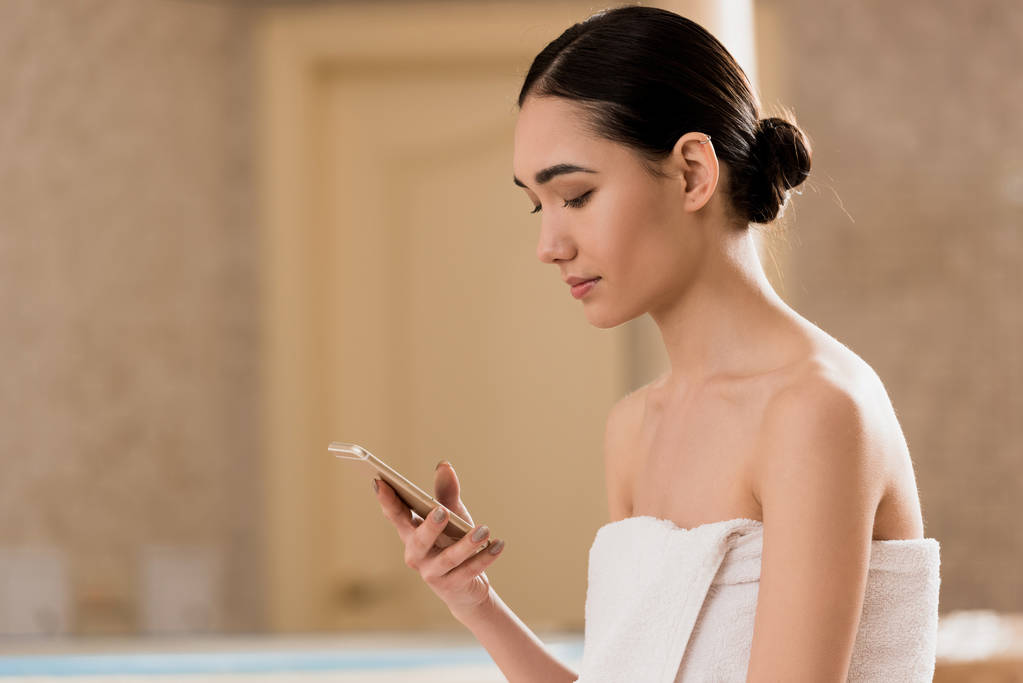 atraktivní žena v ručník pomocí smartphone v lázních s kopií prostor - Fotografie, Obrázek