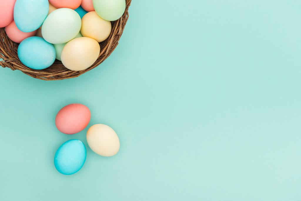 top view of traditional pastel easter eggs in wicker basket isolated on blue with copy space - Photo, Image