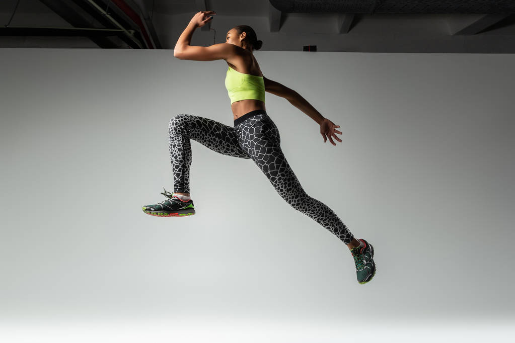 Foto de perfil de mujer fuerte que salta en el estudio
 - Foto, Imagen