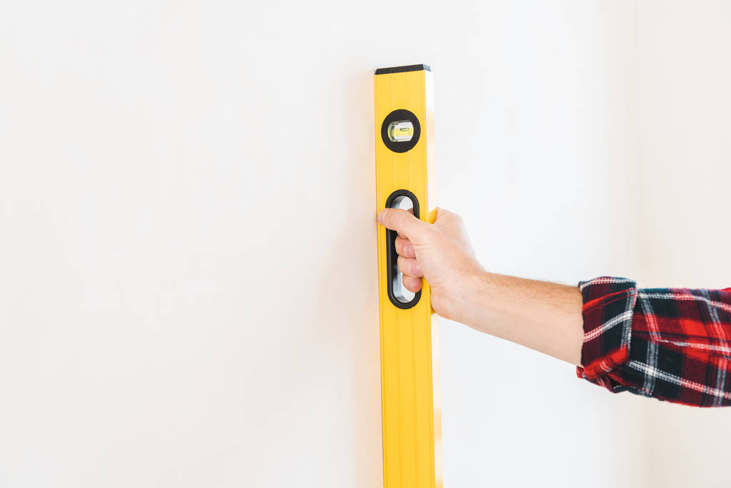 cropped view of man holding measuring level near wall at home - Photo, Image