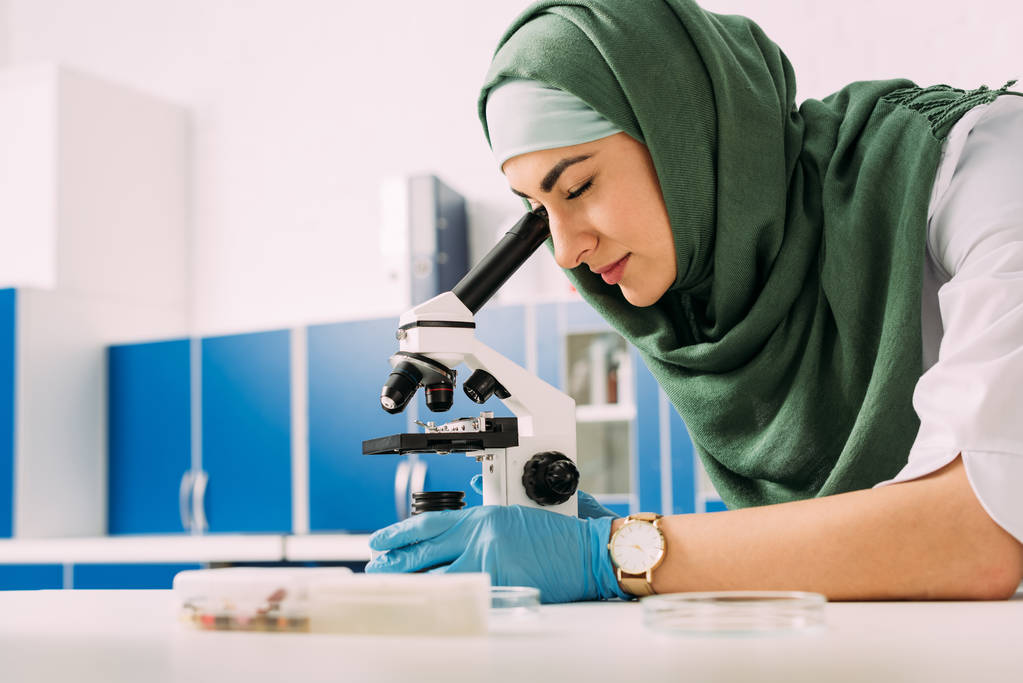skoncentrowany kobiet muzułmańskich naukowców patrząc przez Mikroskop, podczas eksperyment w laboratorium chemiczne - Zdjęcie, obraz