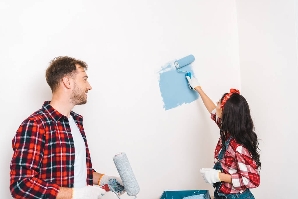 Женщина рисует стену синего цвета рядом с веселым парнем дома
 - Фото, изображение