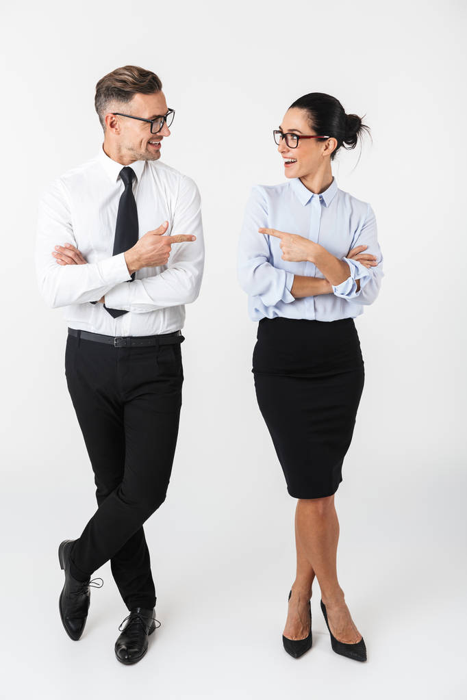 Полная длина коллеги пара в формальной одежде, стоящей изолированно на белом фоне, указывая пальцами
 - Фото, изображение