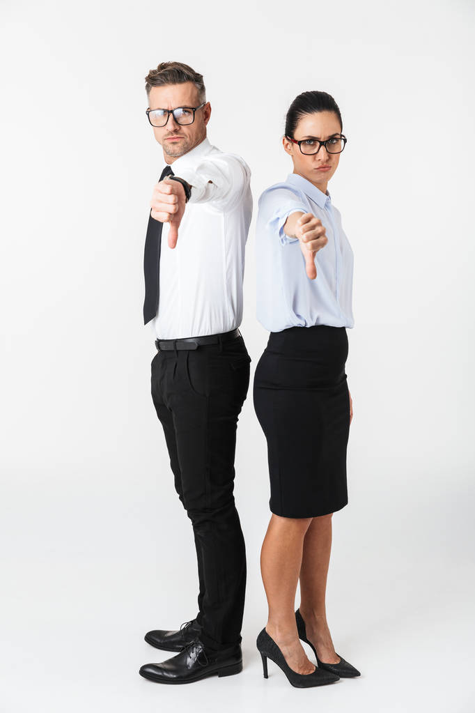 Повна довжина пари колег у формальному одязі, що стоїть ізольовано на білому тлі, великі пальці вниз
 - Фото, зображення