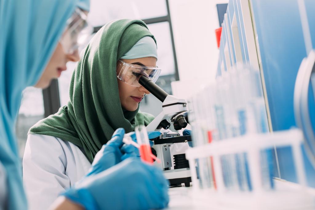 foyer sélectif du scientifique musulman féminin regardant à travers le microscope en laboratoire chimique
 - Photo, image