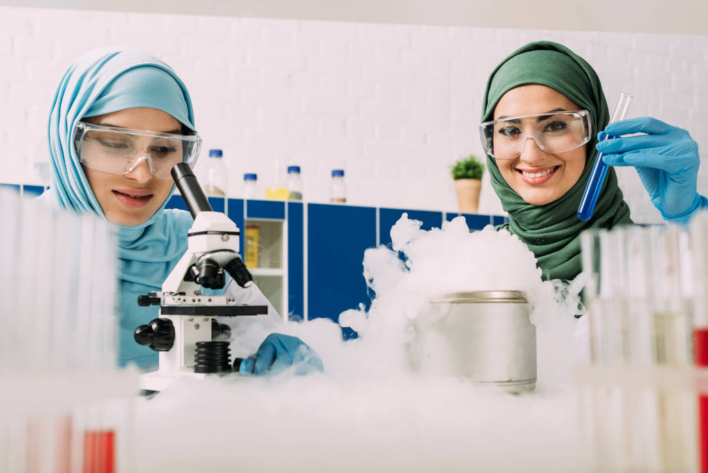 Naispuoliset muslimitutkijat laseissa kokeilemassa mikroskooppia ja kuivajäätä kemiallisessa laboratoriossa
 - Valokuva, kuva