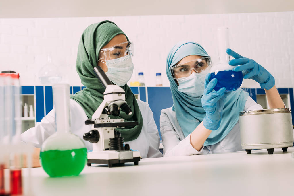 kobiet muzułmańskich naukowców z kolb i mikroskopu podczas eksperymentu w laboratorium chemiczne - Zdjęcie, obraz