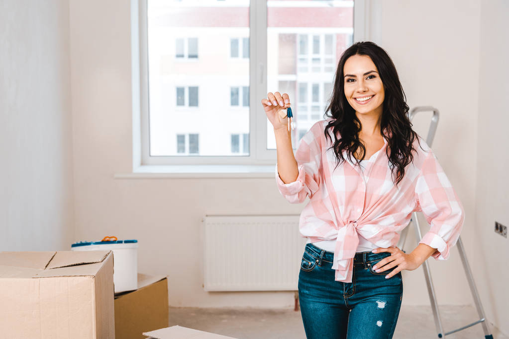 attractive woman holding key while standing in room - Photo, Image