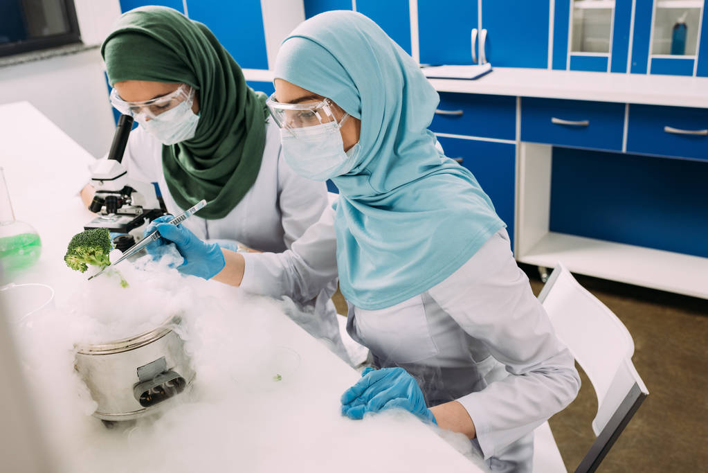 vrouwelijke islamitische wetenschappers experimenteren met droogijs en het gebruik van de Microscoop in chemisch laboratorium - Foto, afbeelding