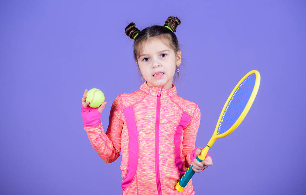 Wychowanie sportowe. Mała ślicznotka lubi tenis. Mały dziecięcy kostium sportowy grać w tenisa. Naucz mnie grać w tenisa. Dziewczyna słodkie dziecko podwójne Bun fryzurę tenisisty. Dzieciństwo i aktywne gry - Zdjęcie, obraz