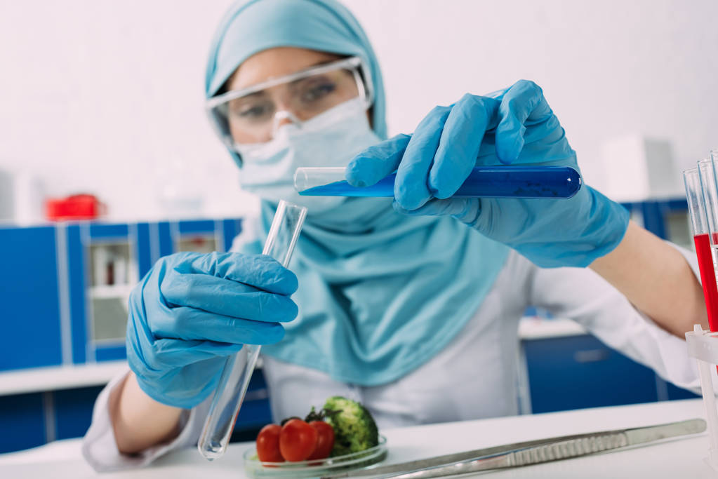 жінка-мусульманка тримає пробірки під час експерименту з овочами в лабораторії
 - Фото, зображення
