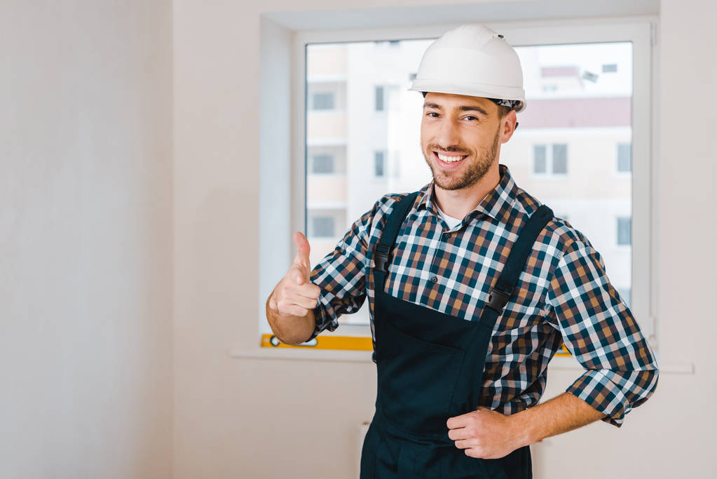 happy handyman smiling while standing and showing thumb up  - Photo, Image