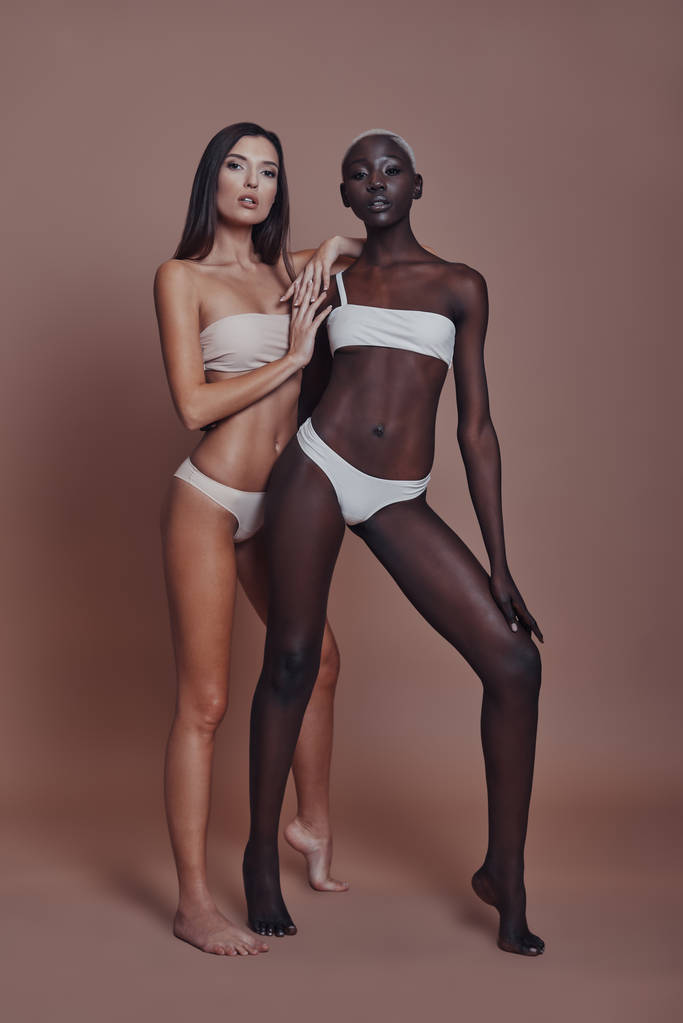 dos modelos de mujeres posando en lencería sobre fondo marrón
 - Foto, Imagen