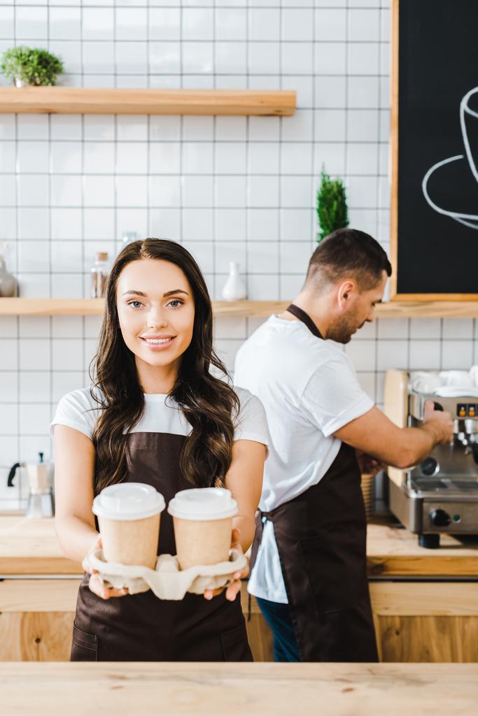 brunette houkutteleva kassanhoitaja seisoo ja tilalla paperimukeja wile barista työskentelee kahvilassa
 - Valokuva, kuva